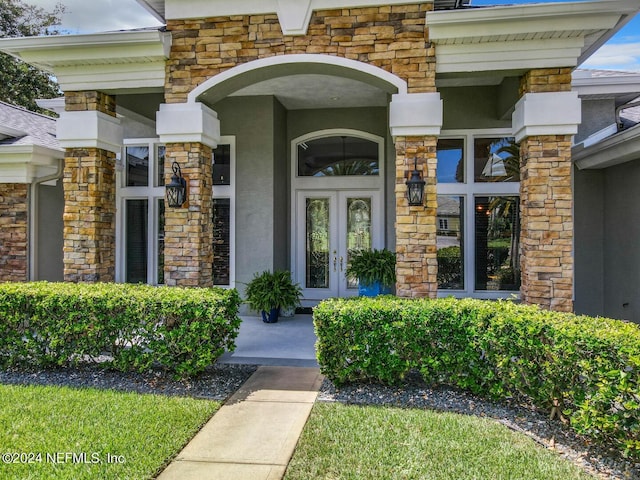 property entrance with stone siding, french doors, and stucco siding