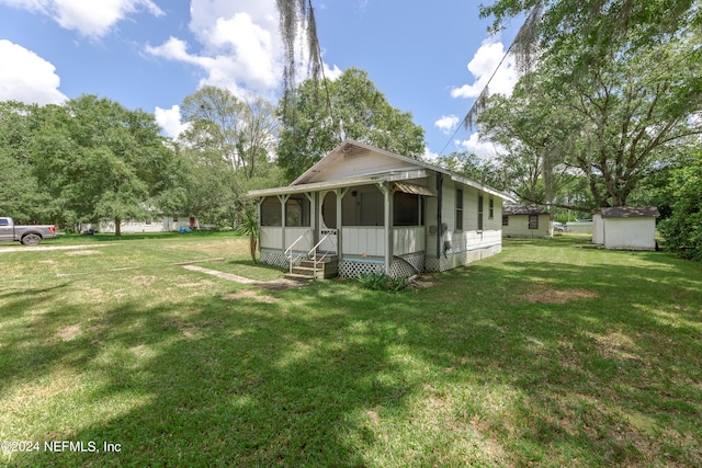 back of property with a lawn, a shed, and a sunroom