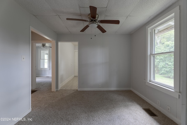 unfurnished room featuring ceiling fan, light carpet, and a drop ceiling