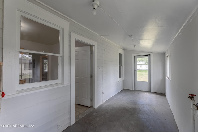 empty room with vaulted ceiling and concrete floors