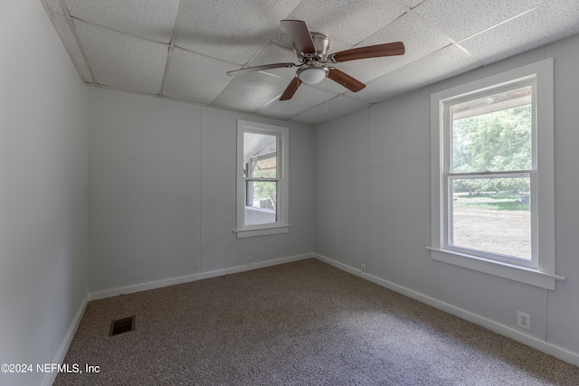 empty room with ceiling fan, a drop ceiling, and carpet floors