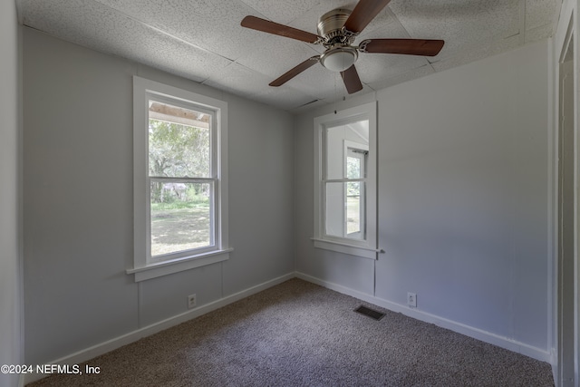 empty room with ceiling fan, carpet, and a healthy amount of sunlight