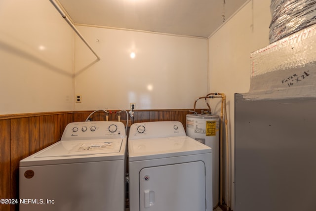 laundry room with wood walls, water heater, and washing machine and dryer