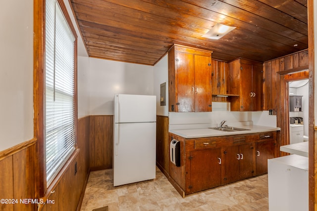 kitchen with heating unit, wooden ceiling, sink, white fridge, and wood walls