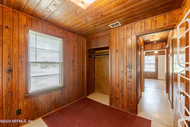 unfurnished bedroom with light wood-type flooring, wood walls, and wood ceiling