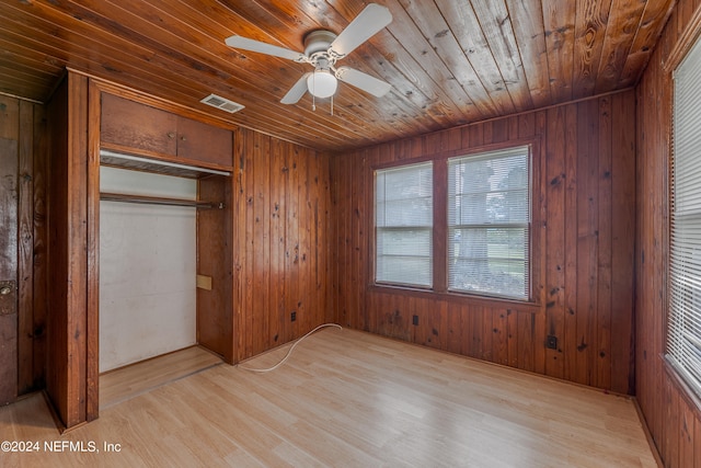 unfurnished bedroom featuring light hardwood / wood-style flooring, ceiling fan, wood walls, and wooden ceiling