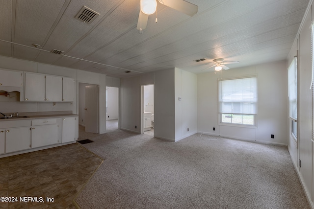 kitchen featuring light carpet, ceiling fan, white cabinetry, and sink