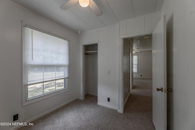 unfurnished bedroom with ornamental molding, carpet flooring, ceiling fan, and a closet