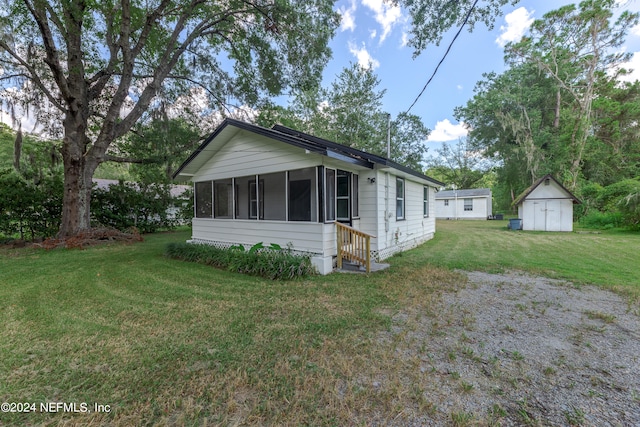 view of front facade featuring a shed, a sunroom, and a front yard