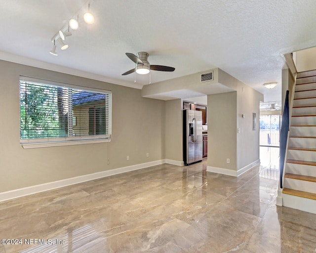 unfurnished room with track lighting, ceiling fan, a textured ceiling, and a healthy amount of sunlight