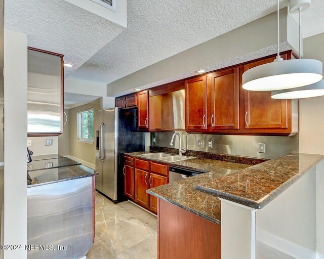 kitchen featuring dark stone countertops, kitchen peninsula, a textured ceiling, and sink