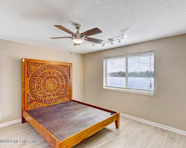 bedroom featuring ceiling fan, a textured ceiling, and light hardwood / wood-style flooring