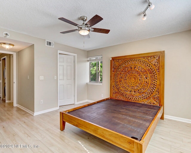 recreation room featuring a textured ceiling, rail lighting, ceiling fan, and light wood-type flooring