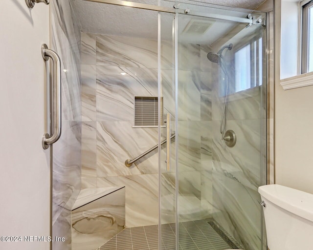 bathroom featuring an enclosed shower, toilet, and a textured ceiling