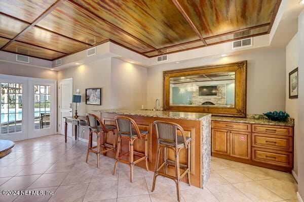 bar featuring wood ceiling, light tile patterned floors, light stone countertops, and french doors