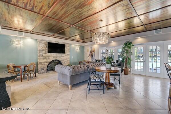 tiled living room featuring wood ceiling, an inviting chandelier, french doors, and a fireplace