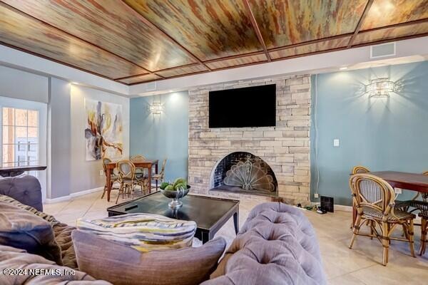 living room featuring wood ceiling, light tile patterned floors, and a fireplace