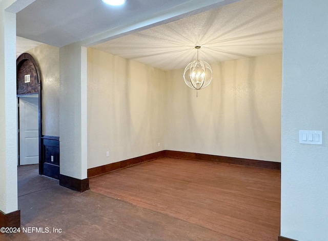 empty room featuring dark wood-type flooring and a chandelier