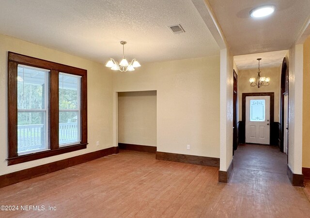 spare room featuring hardwood / wood-style flooring, an inviting chandelier, and a textured ceiling