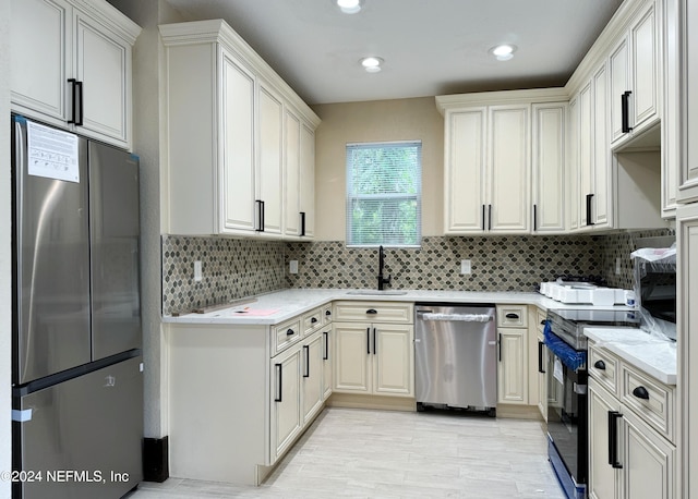 kitchen featuring light stone counters, sink, decorative backsplash, appliances with stainless steel finishes, and light hardwood / wood-style floors