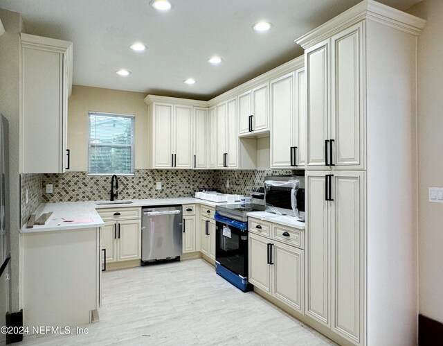 kitchen with light hardwood / wood-style flooring, backsplash, stainless steel appliances, sink, and white cabinetry