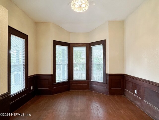 empty room with a notable chandelier and dark hardwood / wood-style flooring