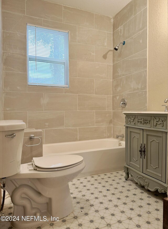 full bathroom featuring tile walls, tiled shower / bath, toilet, and vanity