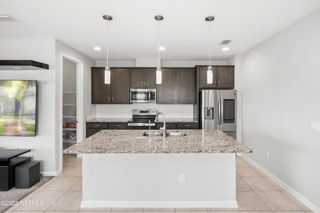 kitchen with sink, appliances with stainless steel finishes, hanging light fixtures, and an island with sink