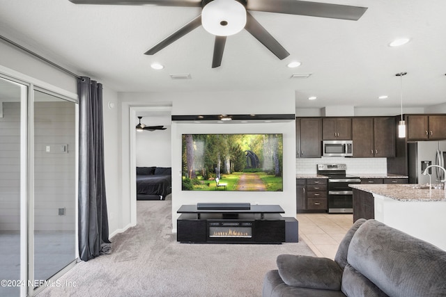 living room with light colored carpet, sink, and ceiling fan