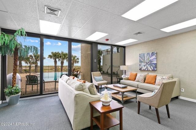 living room with a paneled ceiling and carpet