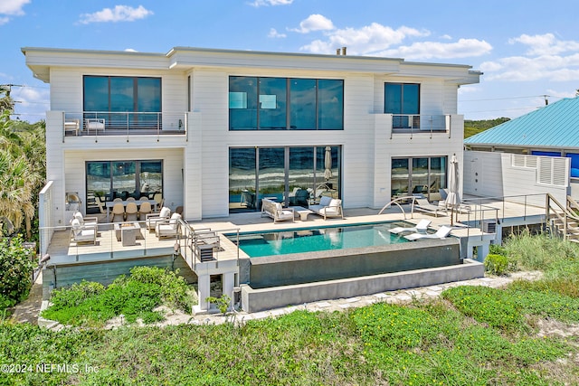 rear view of property featuring a balcony and an outdoor hangout area