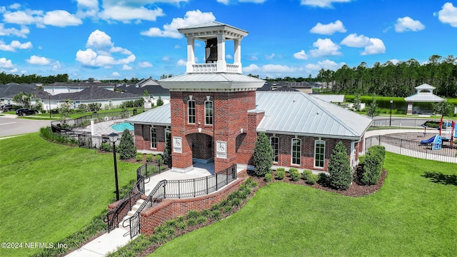 exterior space with metal roof, brick siding, a front lawn, and fence