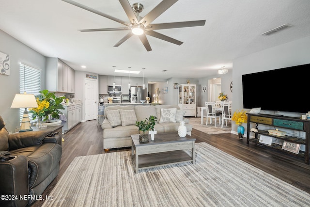 living area with wood finished floors, visible vents, and a ceiling fan