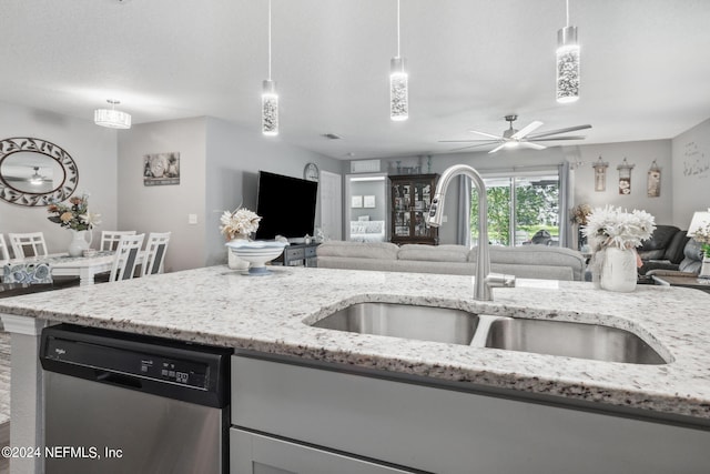 kitchen featuring light stone counters, open floor plan, dishwasher, and a sink