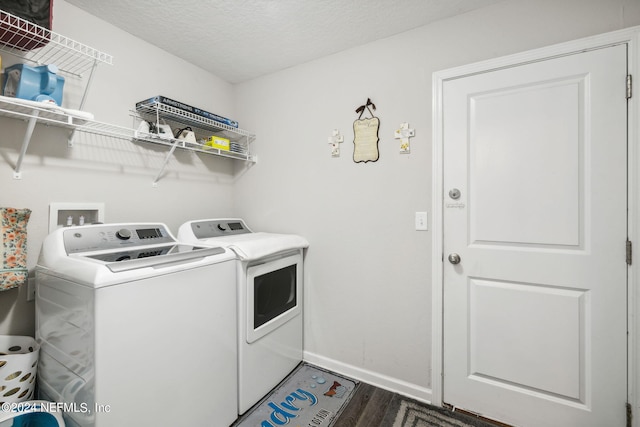 clothes washing area with washer and clothes dryer, a textured ceiling, wood finished floors, laundry area, and baseboards