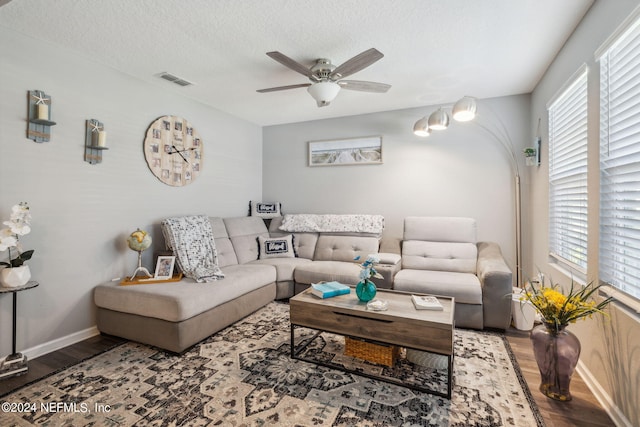 living room with a ceiling fan, visible vents, a textured ceiling, and wood finished floors