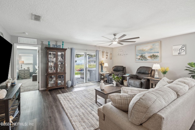 living room with ceiling fan, a textured ceiling, visible vents, and dark wood-style flooring