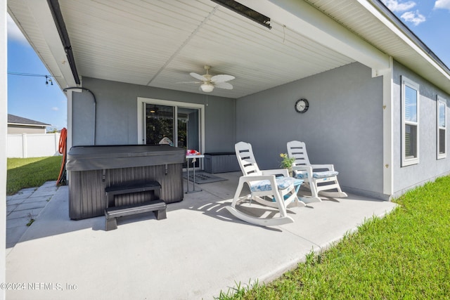 view of patio / terrace featuring a hot tub, fence, and a ceiling fan