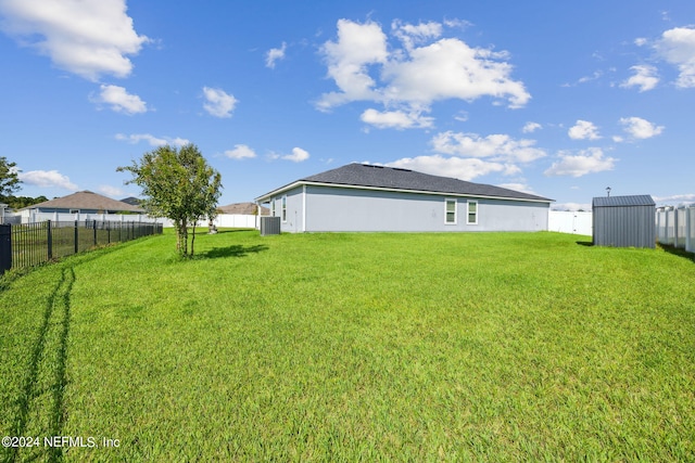 view of yard featuring cooling unit, a fenced backyard, and an outbuilding