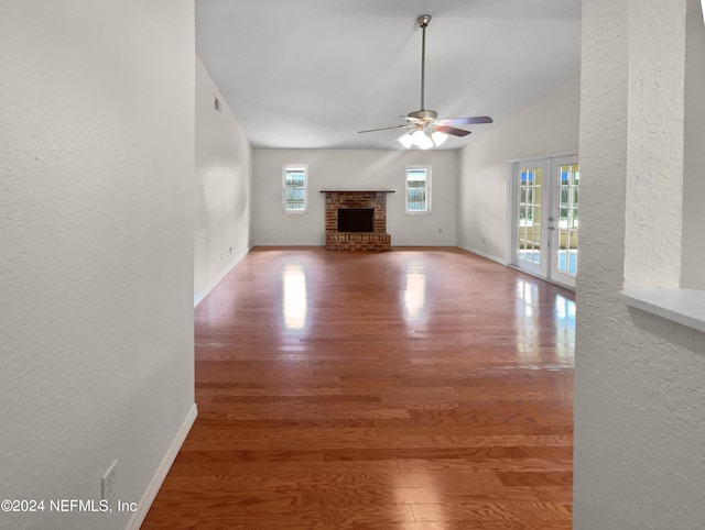 unfurnished living room with plenty of natural light, a fireplace, wood finished floors, and french doors