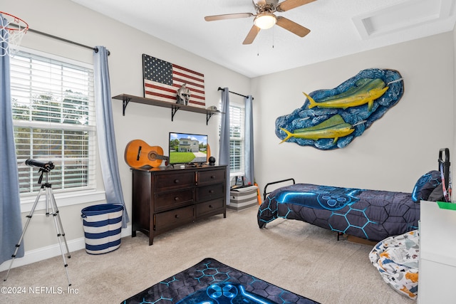 carpeted bedroom featuring attic access, baseboards, and ceiling fan