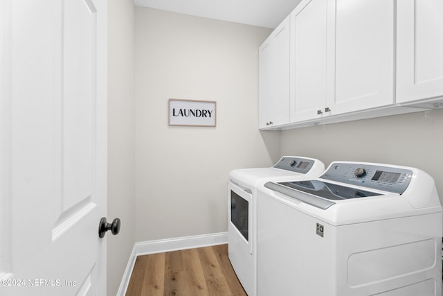 laundry room with wood finished floors, washing machine and clothes dryer, cabinet space, and baseboards