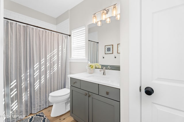 full bathroom with toilet, a shower with shower curtain, wood finished floors, and vanity