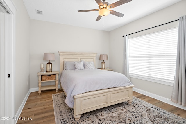 bedroom with light wood-style floors, visible vents, ceiling fan, and baseboards