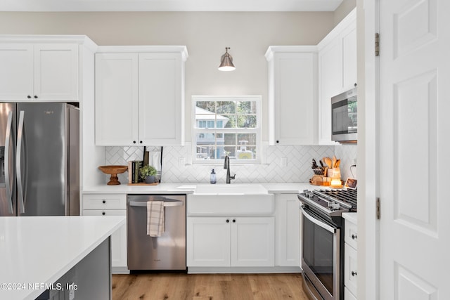 kitchen with stainless steel appliances, a sink, light countertops, and white cabinetry