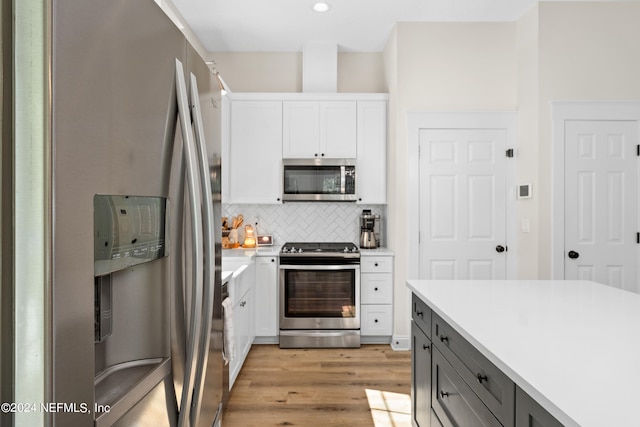 kitchen featuring stainless steel appliances, light countertops, backsplash, white cabinetry, and light wood-type flooring