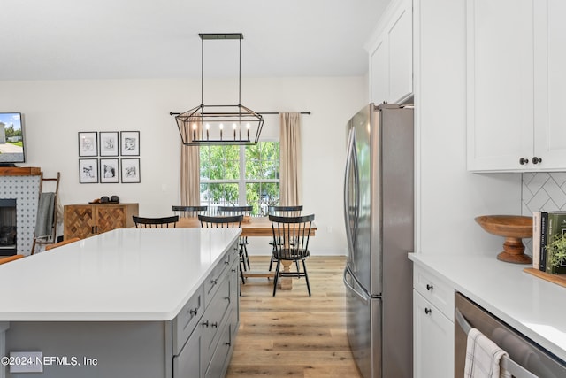 kitchen with appliances with stainless steel finishes, light countertops, gray cabinetry, light wood-style floors, and white cabinetry