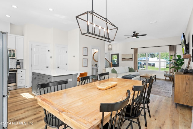 dining area featuring stairs, ceiling fan with notable chandelier, light wood-type flooring, and recessed lighting