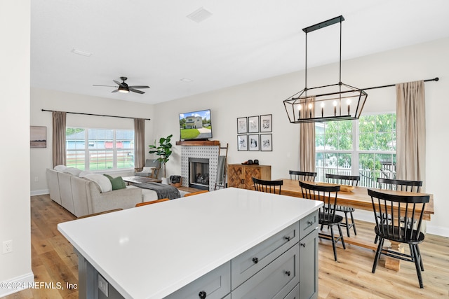 kitchen with light wood finished floors, a fireplace, a center island, and gray cabinetry