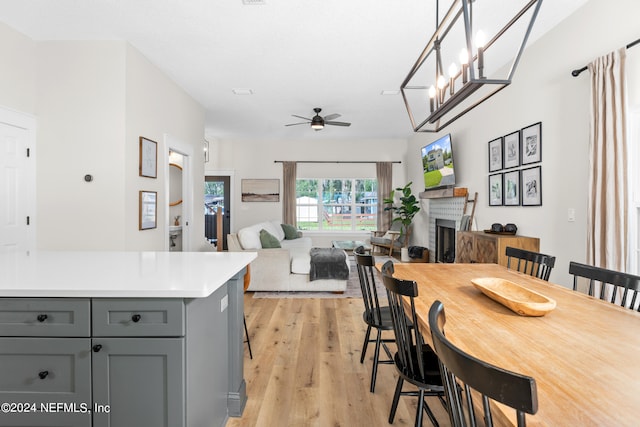 dining room featuring ceiling fan, light wood-type flooring, and a fireplace